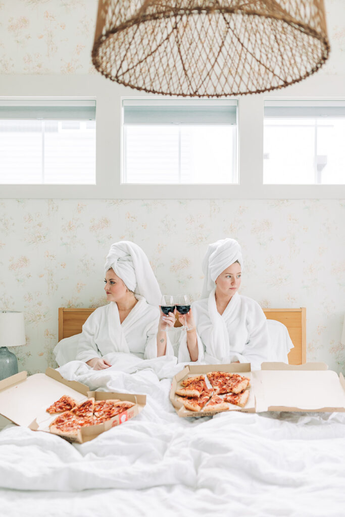 two women in robes with wine and pizza