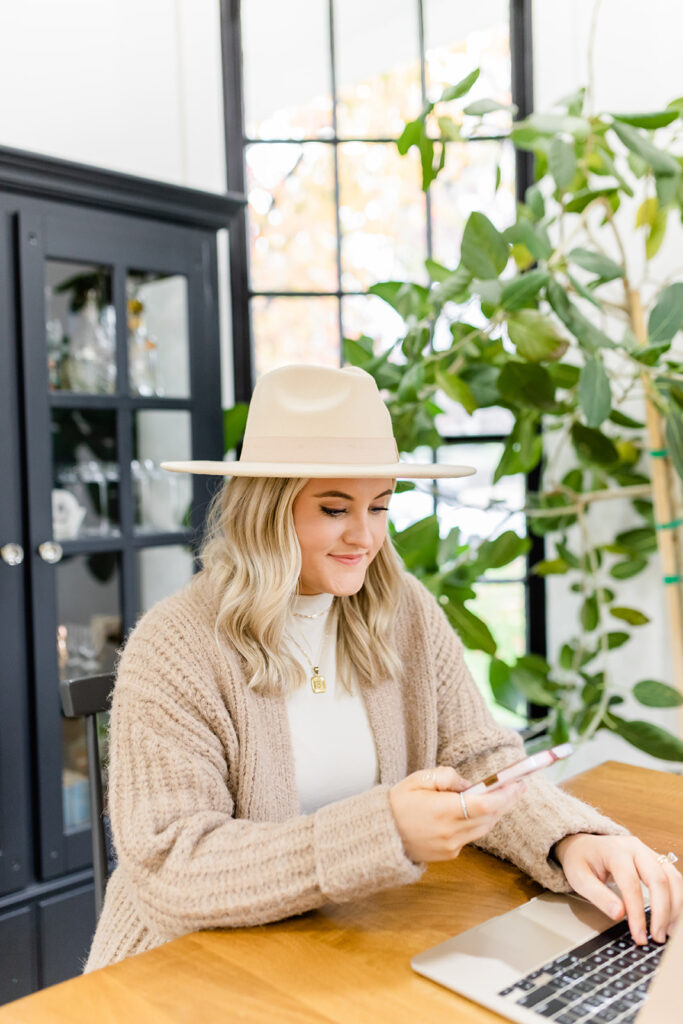 social media expert working on laptop holding phone