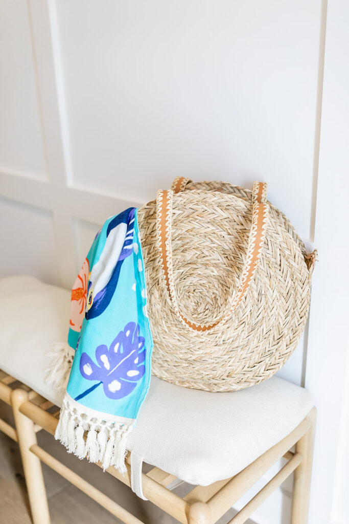 straw beach bag with towel sitting on bench