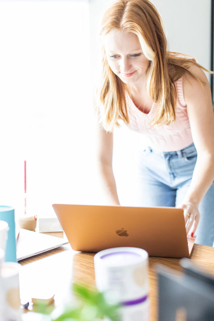 woman standing over laptop typing