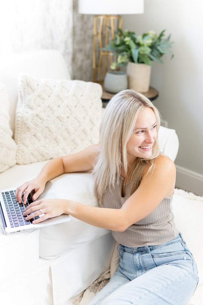 woman smiling while typing on laptop on couch