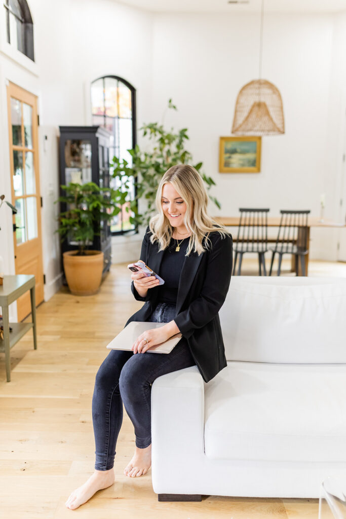 girl sitting on couch smiling with her attention on social media