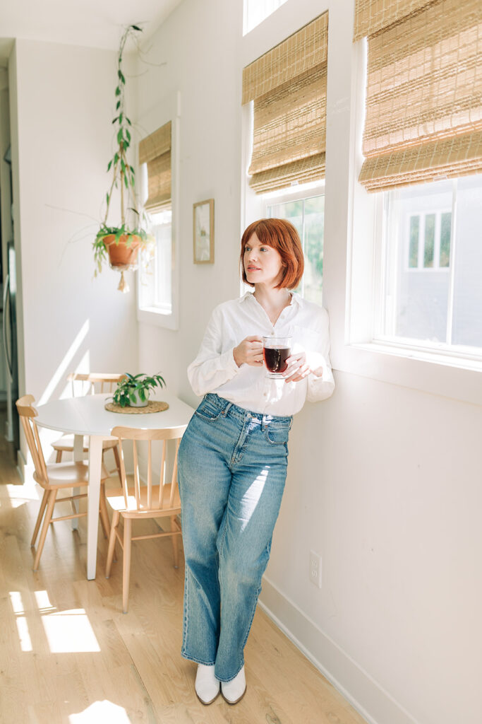 woman standing with coffee mug in bright and airy room with houseplants