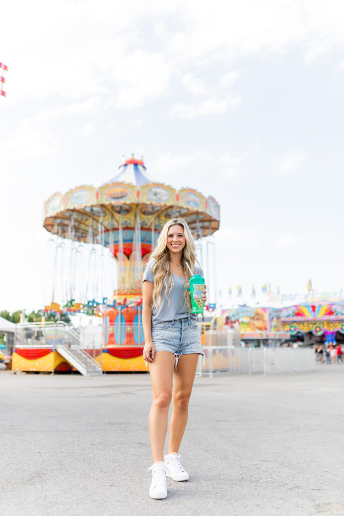 woman posing for summer lifestyle photoshoot at the fair holding a beverage