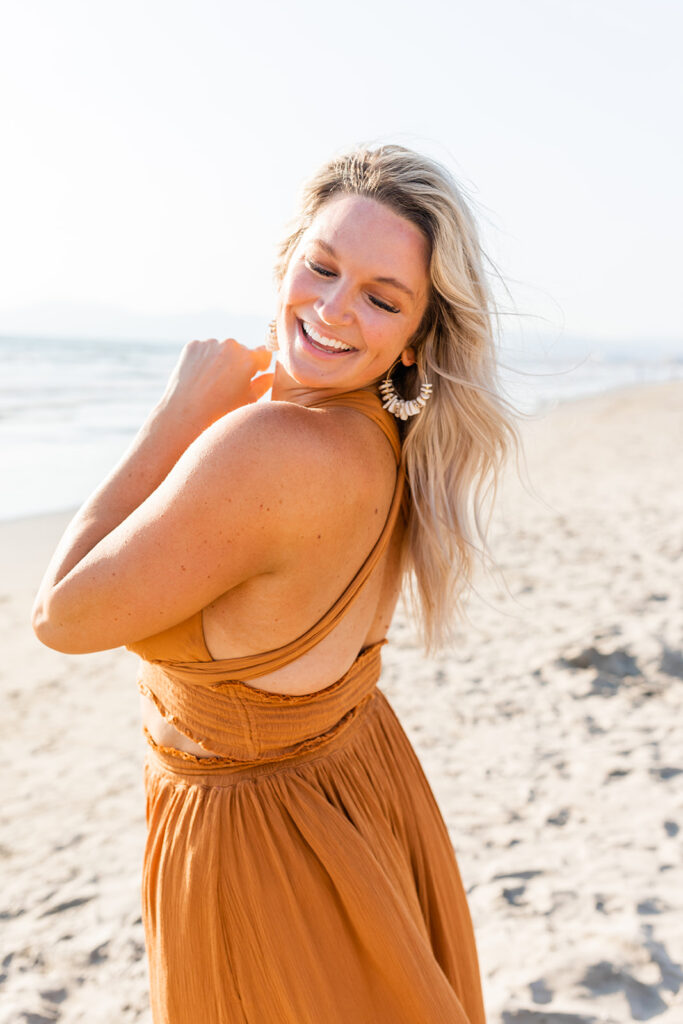 woman on beach in orange dress with blonde flowy hair