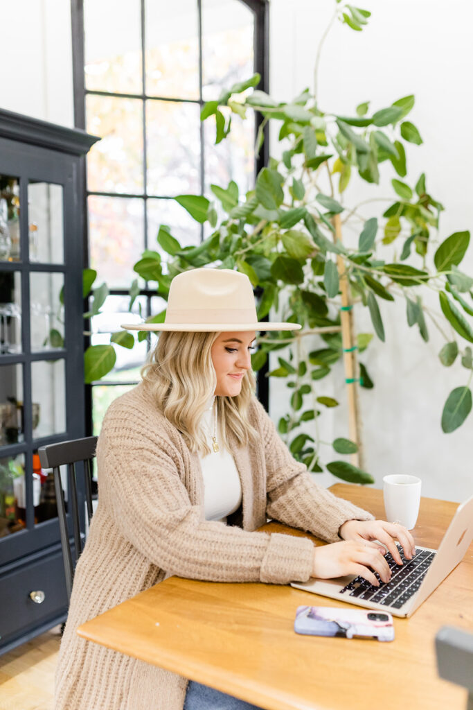 stylish woman at table typing on laptop