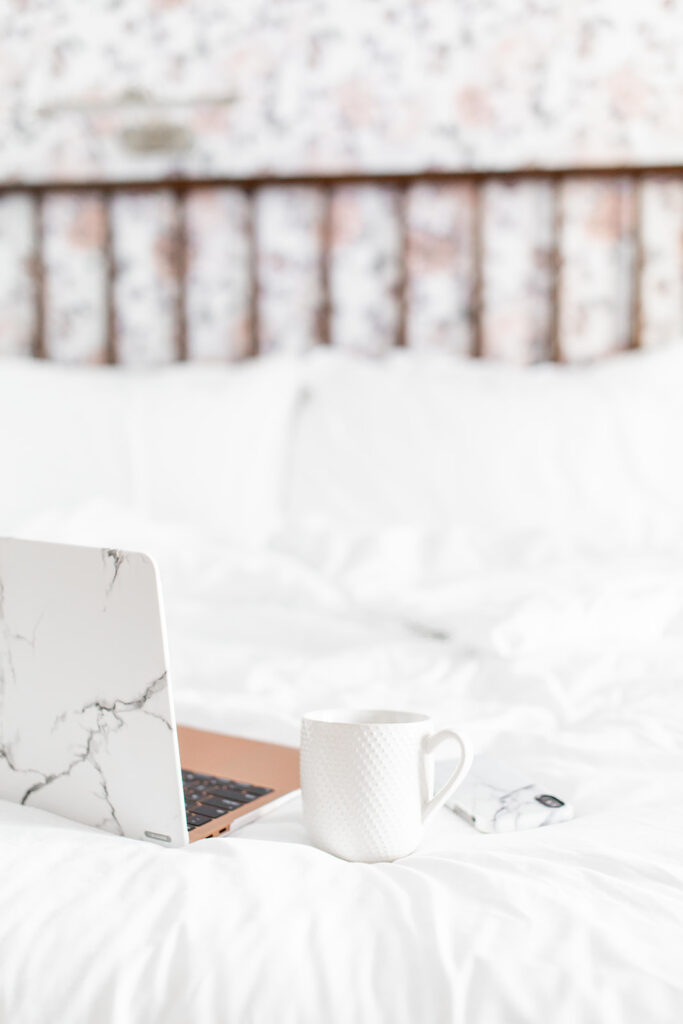 laptop and phone in marble case on bed with coffee