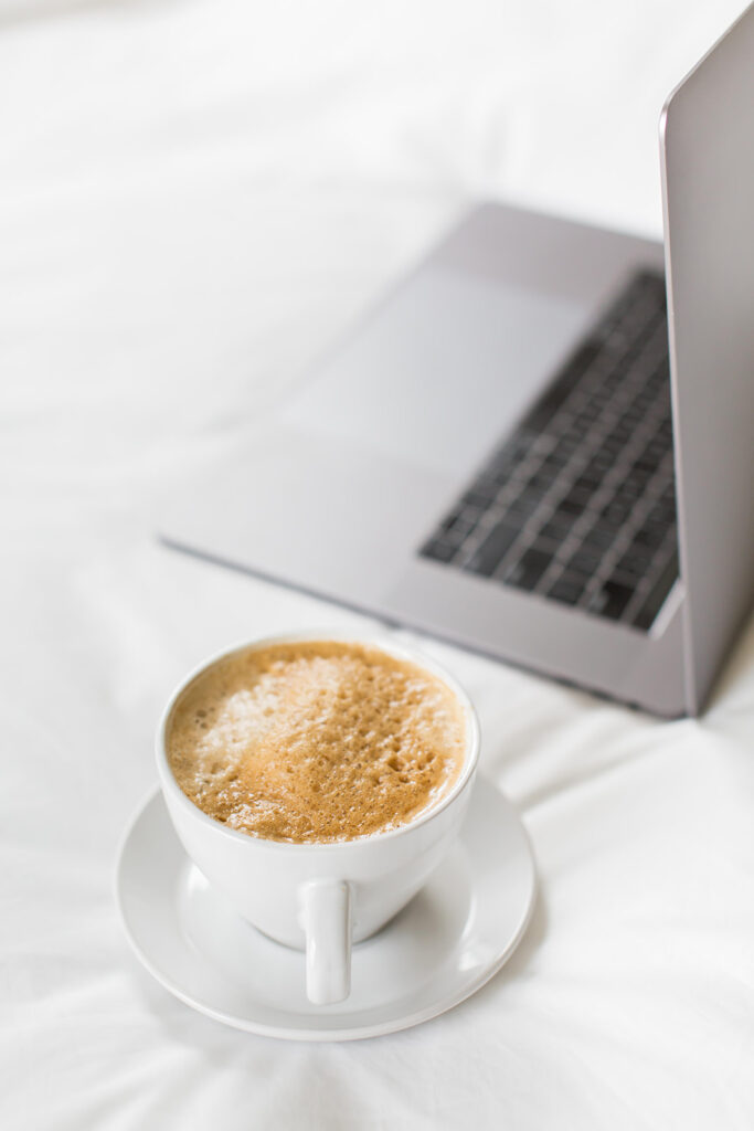 laptop and cappuccino on bed