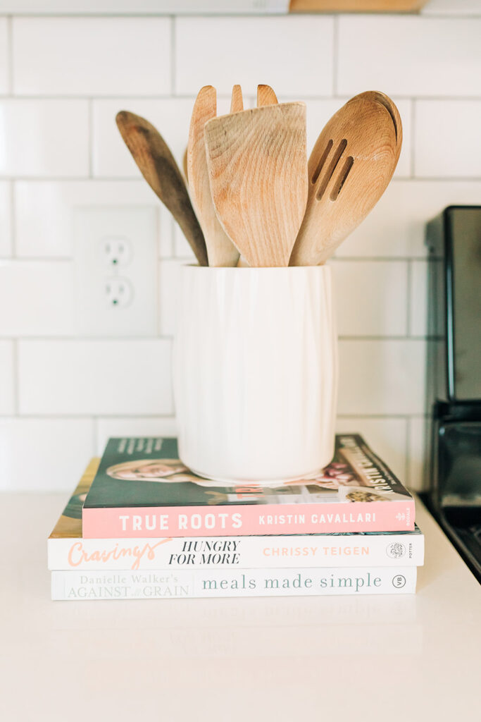 stack of cookbooks with utensils on top