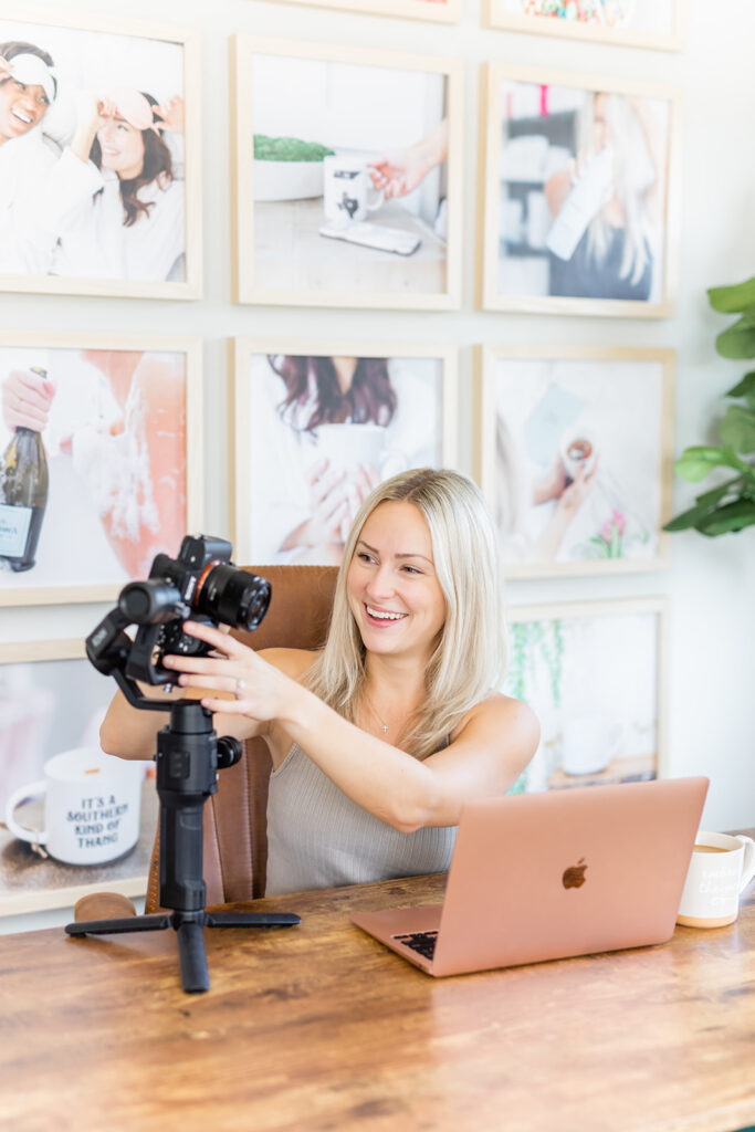 woman adjusting video camera at desk with laptop