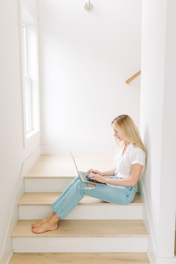 woman sitting on staircase working on laptop