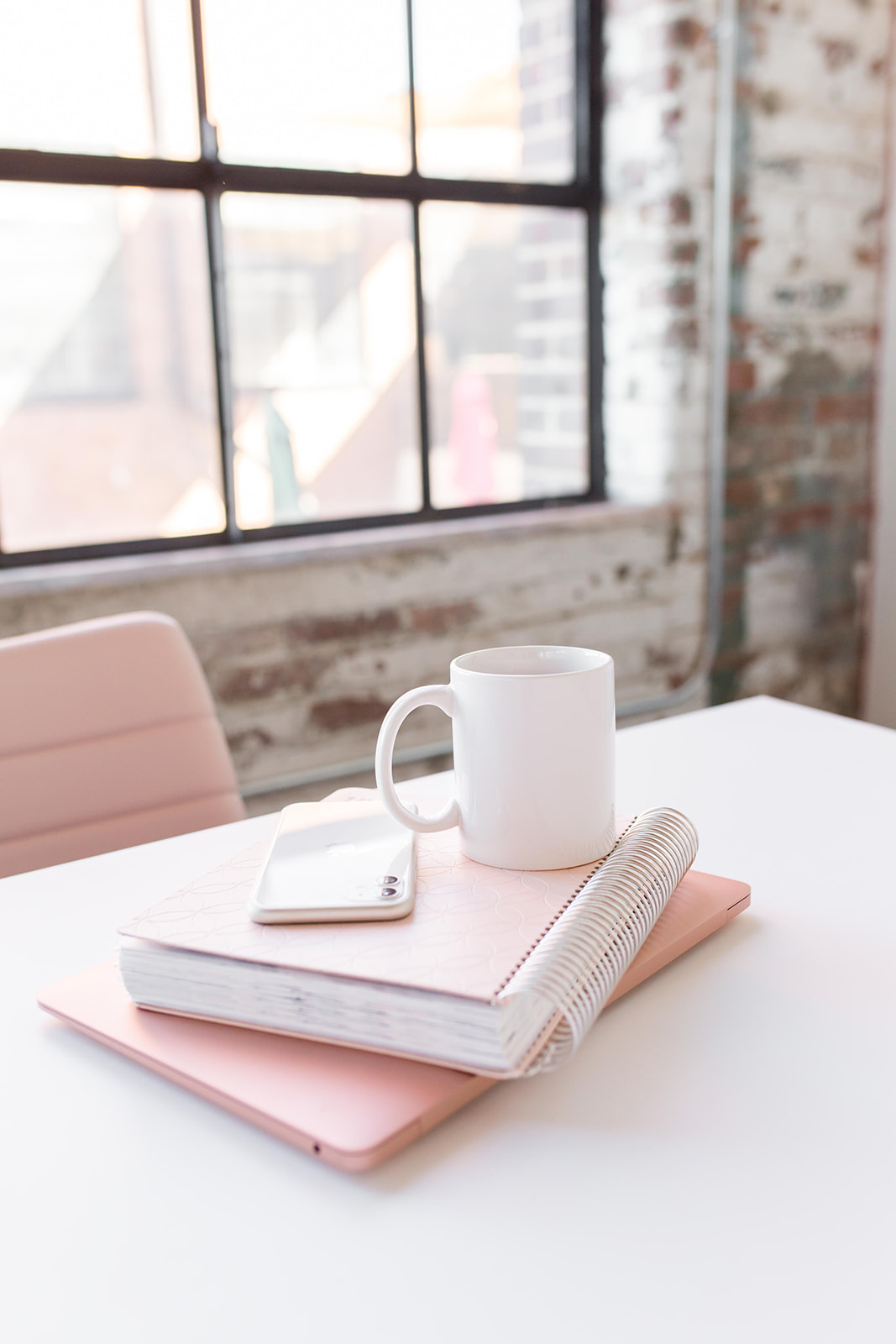 desk pile with laptop, notebook, and coffee mug