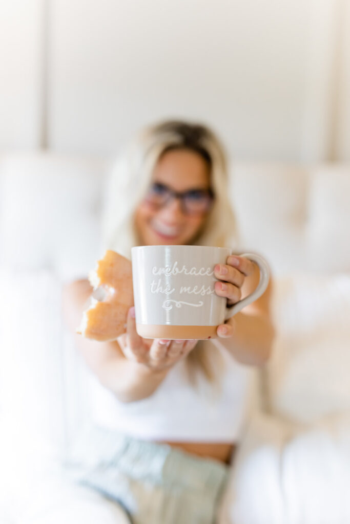 smiling woman holding up mug that says "embrace the mess"